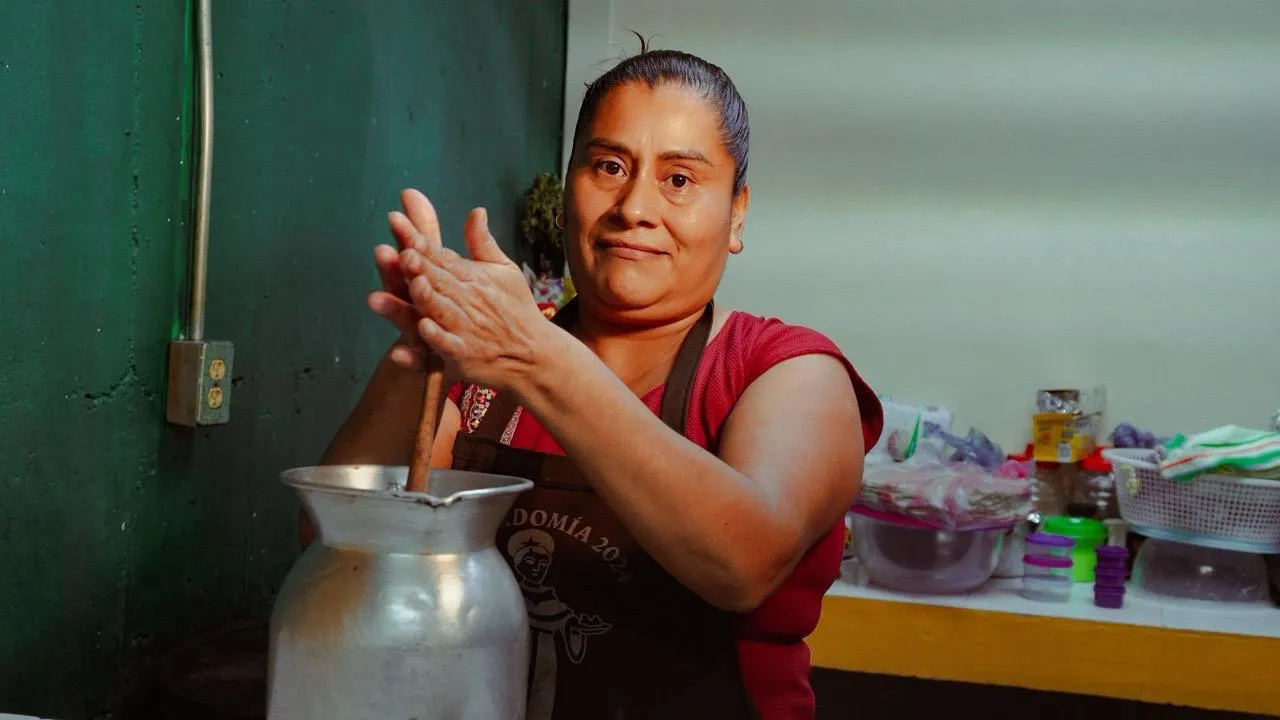 Mujer batiendo chocolate tradicional en una jarra de metal en Juquila